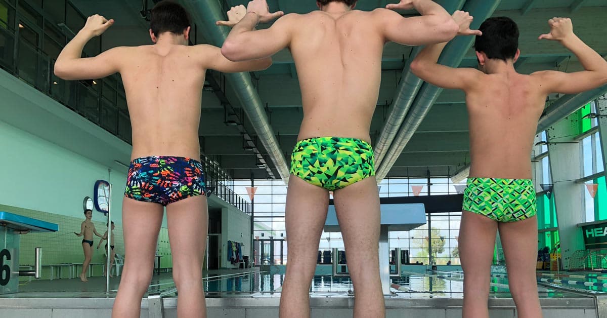 Boys wearing swimming trunks swimming poolside